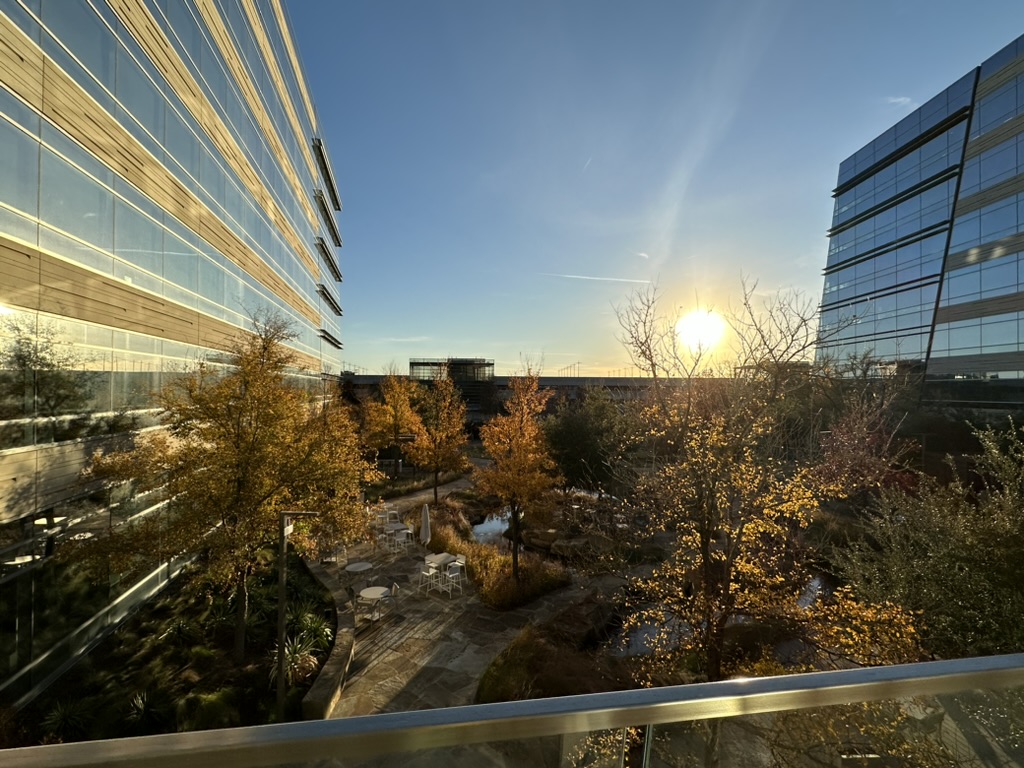 a sun setting behind a glass building