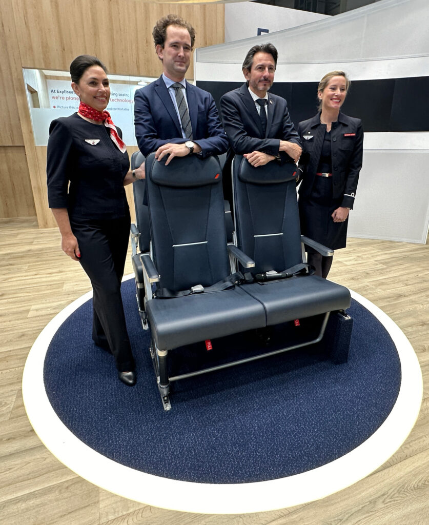 a group of people standing in front of a Expliseat TiSeat 2X