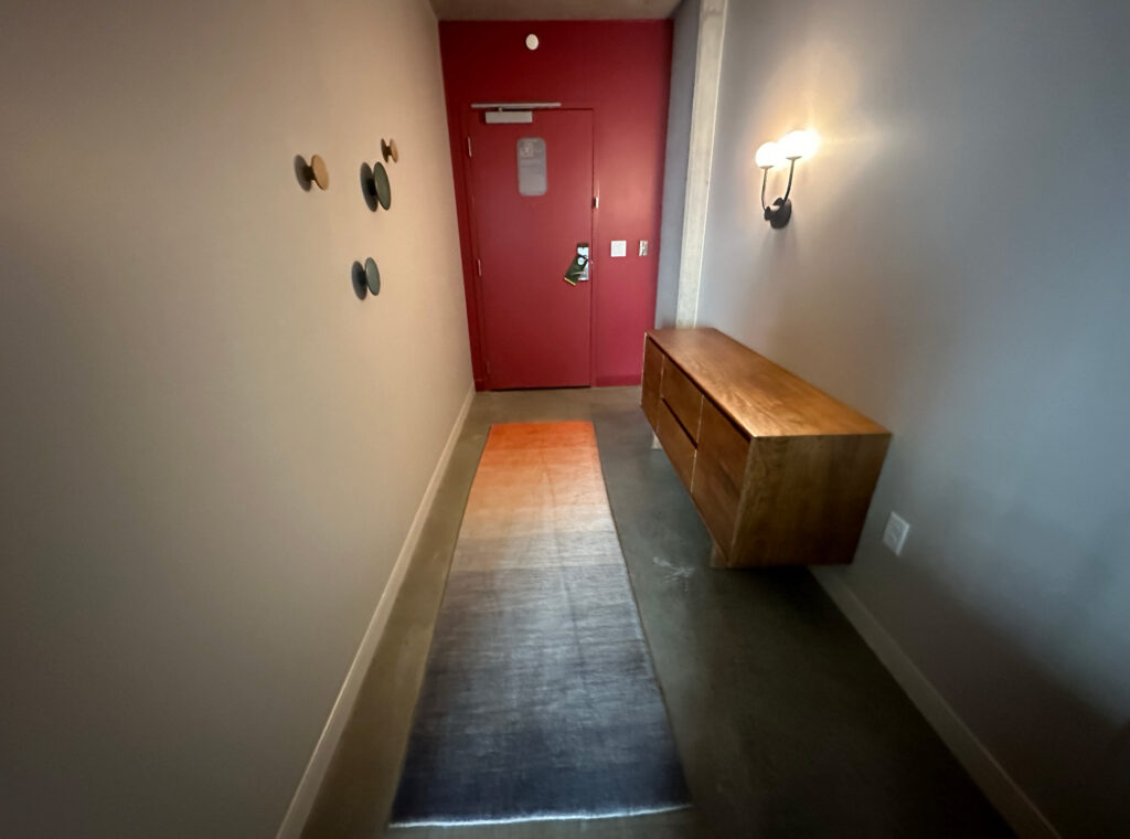 a hallway with a red door and a rug