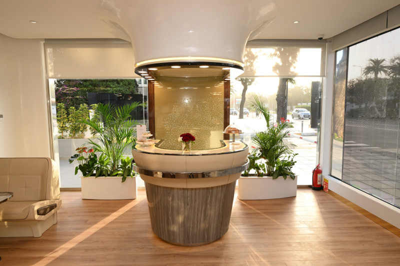 a reception desk in a room with plants and a window